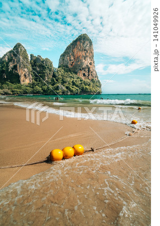 Scenic tropical beach with yellow buoys in the water and towering limestone cliffs in Scenic tropical beach with yellow buoys in the water and towering limestone cliffs in 141049926