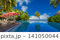 Idyllic tropical beach, sun loungers, red umbrella, palm trees, infinity pool lagoon. Luxury summer resort paradise, romantic couple honeymoon escape. Relaxing travel destination wallpaper 141050044