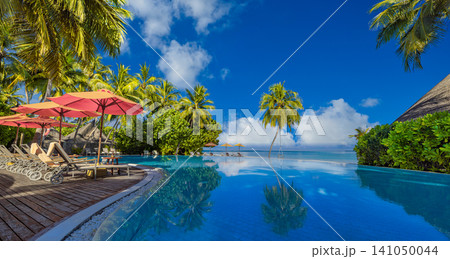 Idyllic tropical beach, sun loungers, red umbrella, palm trees, infinity pool lagoon. Luxury summer resort paradise, romantic couple honeymoon escape. Relaxing travel destination wallpaper Idyllic tropical beach, sun loungers, red umbrella, palm trees, infinity pool lagoon. Luxury summer resort paradise, romantic couple honeymoon escape. Relaxing travel destination wallpaper 141050044