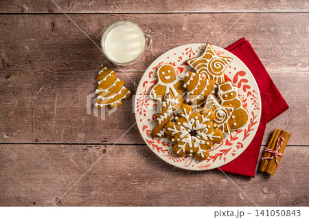Holiday background. Christmas gingerbread cookies in a plate with glass of milk. Flat lay 141050843