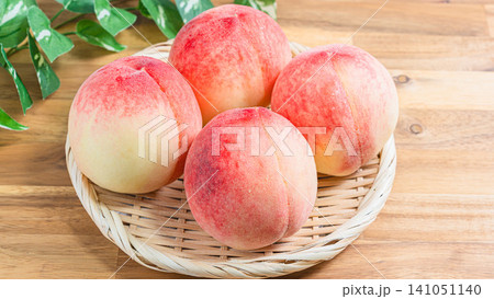 かごに盛り付けた旬の桃 夏の味覚を楽しむ新鮮な白桃 かごに盛り付けた旬の桃 夏の味覚を楽しむ新鮮な白桃 141051140