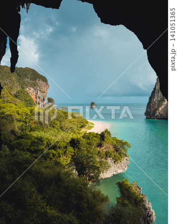 Elevated view from a dark cave looking out over a tropical beach and limestone islands. Elevated view from a dark cave looking out over a tropical beach and limestone islands. 141051365