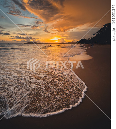 Dramatic golden sunset seascape over a tropical beach with gentle washing waves. 141051372