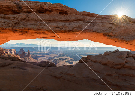 Majestic sunrise illuminates Mesa Arch in Canyonlands National Park, Utah, painting iconic landscape with warm sunlight. Morning light creates breathtaking natural view at dawn 141051983