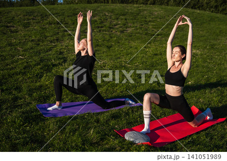 Women practicing yoga outdoors on a sunny day in a green park 141051989