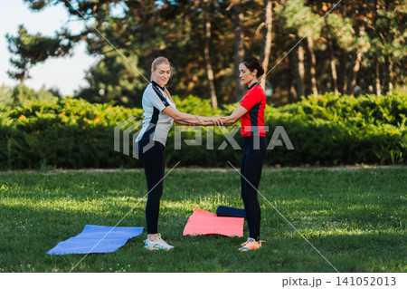 Women practicing exercise in park during sunny day Women practicing exercise in park during sunny day 141052013