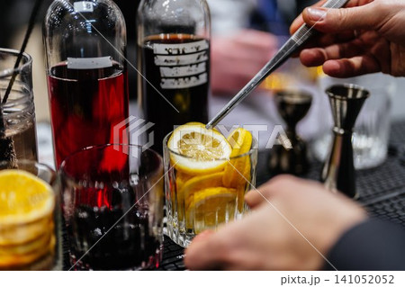 Crafting a refreshing cocktail with fresh lemon slices at a bar Crafting a refreshing cocktail with fresh lemon slices at a bar 141052052