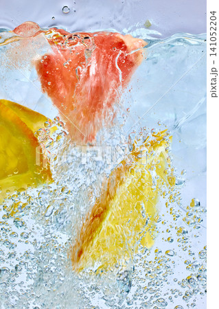 Grapefruit and lemon slices splashing in sparkling ice drink macro Grapefruit and lemon slices splashing in sparkling ice drink macro 141052204