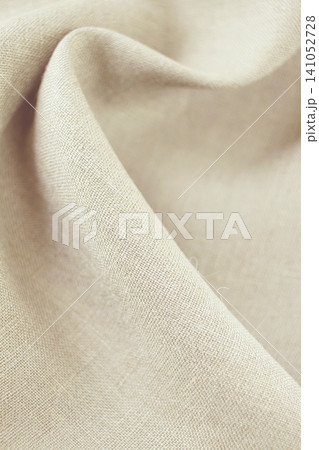 Close-up of beige linen fabric with soft folds and texture, natural organic fabric. 141052728