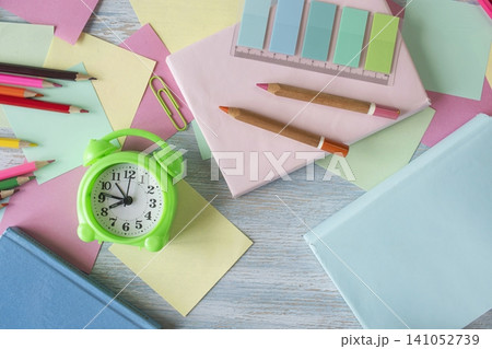 Alarm clock, books, colored paper and pencils on a school desk, top view, flat lay, in pastel colors. Back to school concept. 141052739
