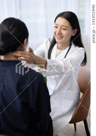 患者の首に手を当てて診察する若い日本人の女性医師 141052940