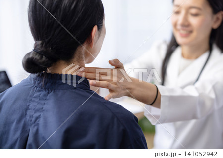 患者の首に手を当てて診察する若い日本人の女性医師 141052942