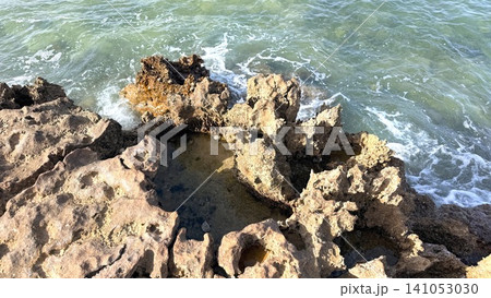 Sunlit coastal limestone rocks with tidal pools and green sea Sunlit coastal limestone rocks with tidal pools and green sea 141053030