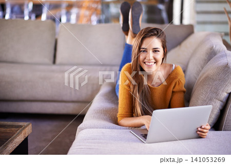 Happy, home and woman with a laptop, portrait and connection with typing in a lounge. Person on a sofa, apartment and girl with a computer and research with online blog and news with smile and relax Happy, home and woman with a laptop, portrait and connection with typing in a lounge. Person on a sofa, apartment and girl with a computer and research with online blog and news with smile and relax 141053269