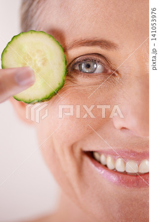 Skincare, cucumber and portrait of woman in studio for health, wellness or natural facial routine. Smile, beauty and mature person with organic vegetable for dermatology treatment by white background Skincare, cucumber and portrait of woman in studio for health, wellness or natural facial routine. Smile, beauty and mature person with organic vegetable for dermatology treatment by white background 141053976