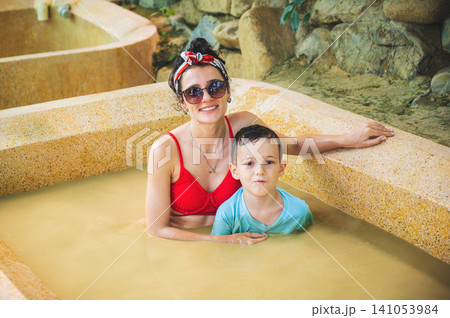 happy family is relaxing in mud bath at a spa complex. Mom and son on vacation at a health resort in Vietnam happy family is relaxing in mud bath at a spa complex. Mom and son on vacation at a health resort in Vietnam 141053984