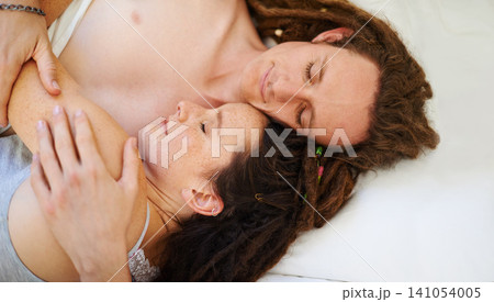Sleeping, top view and couple hug in bed in home for peace, calm or relax to dream together in the morning. Above, man and woman cuddle to rest in bedroom for comfort or embrace for love in apartment Sleeping, top view and couple hug in bed in home for peace, calm or relax to dream together in the morning. Above, man and woman cuddle to rest in bedroom for comfort or embrace for love in apartment 141054005