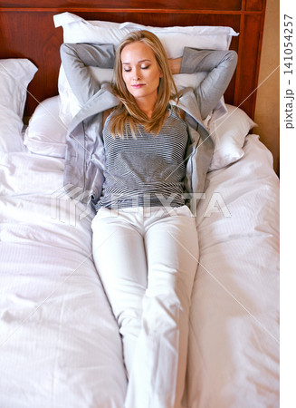 Woman, bed and relax with sleep for rest, comfort and tired with peace and calm at home. Fatigue, nap and dream, comfortable with blanket and pillow with wellness, exhausted and cozy in bedroom 141054257