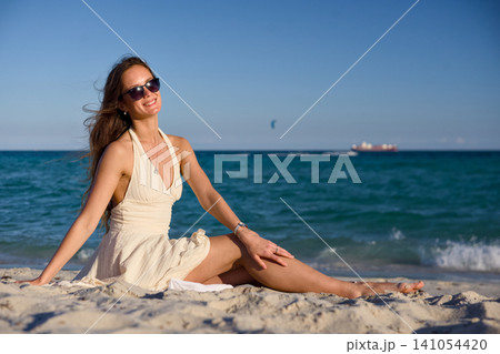 Woman with Windswept Hair Relaxing by Ocean Waves Woman with Windswept Hair Relaxing by Ocean Waves 141054420