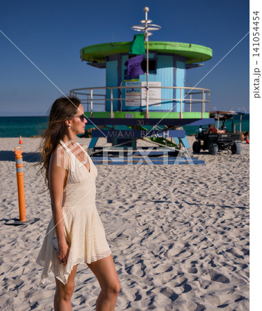 Young Woman Walking on Sandy Beach Near Lifeguard Tower 141054454
