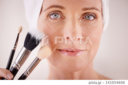 Portrait, mature woman and makeup with brushes, cosmetics and dermatology on grey studio background. Face, person and model with product and tool with wellness and skincare with treatment or grooming 141054698