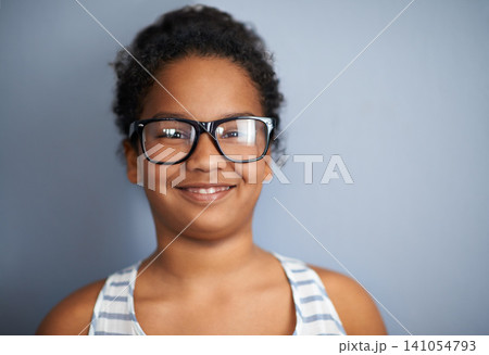 Happy child, girl and portrait in studio with glasses, education and pride in school or academic excellence. Kid, face and smile in prescription eyewear to support learning, eyecare and ophthalmology 141054793