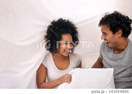 Couple, bed and pillow playful with sheet for carefree weekend with partnership, happiness or bonding. Man, woman and linen in apartment for holiday vacation on morning comfort, peace or relaxing Couple, bed and pillow playful with sheet for carefree weekend with partnership, happiness or bonding. Man, woman and linen in apartment for holiday vacation on morning comfort, peace or relaxing 141054800