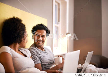 Apartment, laptop and couple with smile for working from home in bedroom, eye contact and together with love. Partners, woman and man on bed of house with technology for career and coffee in morning Apartment, laptop and couple with smile for working from home in bedroom, eye contact and together with love. Partners, woman and man on bed of house with technology for career and coffee in morning 141054833