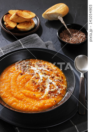 spiced sweet potato soup in a black bowl spiced sweet potato soup in a black bowl 141054903