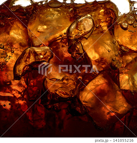 Iced dark beverage with amber cubes and sparkling bubbles 141055216