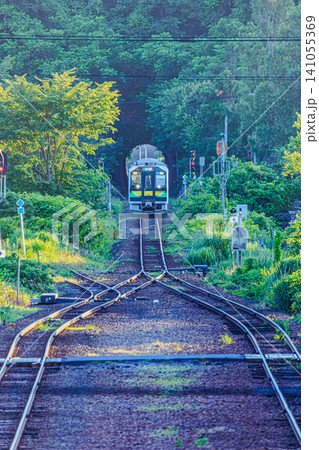 夏の朝の光が差し込む函館本線山線の一本の線路を進む一両のローカル列車 夏の朝の光が差し込む函館本線山線の一本の線路を進む一両のローカル列車 141055369