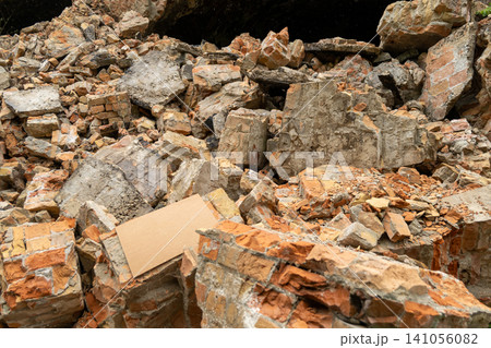 Debris covers the ground where a building has collapsed in an urban area. Bricks and stones are scattered all around 141056082