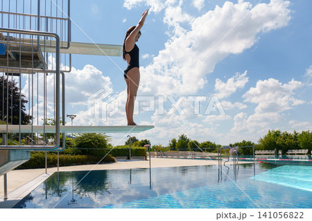 Teen girl preparing to jump from diving board at pool Teen girl preparing to jump from diving board at pool 141056822