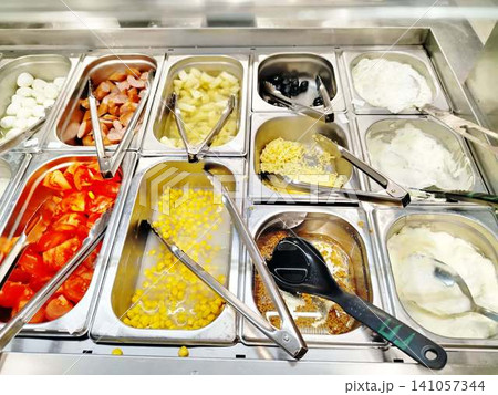 Self-Serve Salad Bar Counter With Fresh Toppings Corn Tomatoes Olives Yogurt And Sausage. Self-Serve Salad Bar Counter With Fresh Toppings Corn Tomatoes Olives Yogurt And Sausage. 141057344