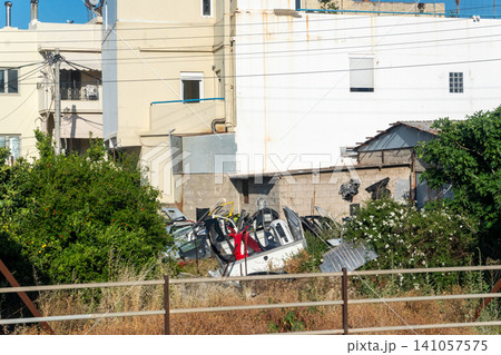 Scrap yard with piled car parts near residential buildings 141057575