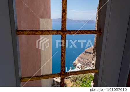Sea and volcanic caldera view through a rusty barred window Sea and volcanic caldera view through a rusty barred window 141057610