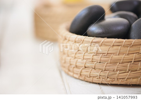 Stone, massage and closeup on basket in spa for luxury service in hospitality at hotel on holiday or vacation. Rocks, container and object for wellness treatment on table or detail of pebble Stone, massage and closeup on basket in spa for luxury service in hospitality at hotel on holiday or vacation. Rocks, container and object for wellness treatment on table or detail of pebble 141057993