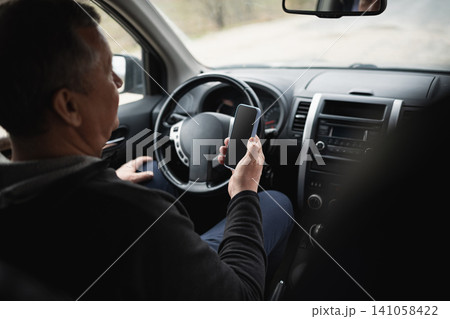 Senior man using smartphone while sitting in parked car Senior man using smartphone while sitting in parked car 141058422