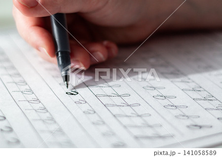 Quiet scene of woman writing with pen. Training accurate handwriting. Therapeutic habit to reduce anxiety and increase clarity. Calmness and digital detox Quiet scene of woman writing with pen. Training accurate handwriting. Therapeutic habit to reduce anxiety and increase clarity. Calmness and digital detox 141058589