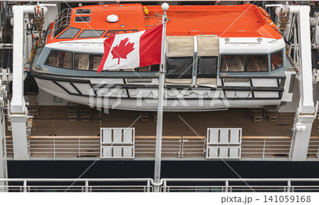 Orange Lifeboat on Cruise Ship Deck and Canadian flag. Lifeboats displayed aboard on a cruise ship, for safety and preparedness measures Orange Lifeboat on Cruise Ship Deck and Canadian flag. Lifeboats displayed aboard on a cruise ship, for safety and preparedness measures 141059168