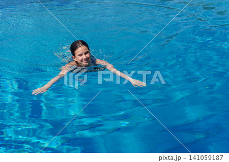 Teen girl swimming in blue outdoor pool Teen girl swimming in blue outdoor pool 141059187