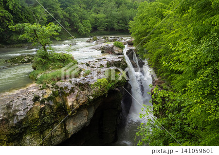 Powerful waterfall in Martvili Canyon surrounded by lush green forest, Samegrelo, Georgia. Powerful waterfall in Martvili Canyon surrounded by lush green forest, Samegrelo, Georgia. 141059601