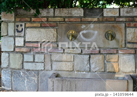 Old stone fountain on brick wall outdoors Old stone fountain on brick wall outdoors 141059644