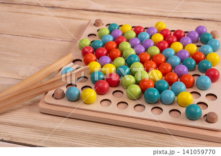 Educational wooden toy lies on desk. Colorful round ball elements help children develop fine motor skills. Eco friendly learning material provides fun intellectual activity for toddlers. 141059770