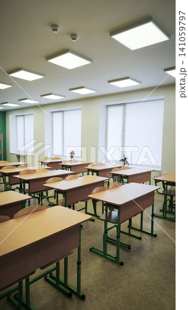 classroom filled with desks and chairs under bright daylight from windows. classroom filled with desks and chairs under bright daylight from windows. 141059797