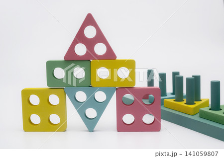 Educational toy stands on white background. Colorful wooden elements help children learn geometric shapes. Smart logic blocks provide quality preschool development for creative toddlers. Educational toy stands on white background. Colorful wooden elements help children learn geometric shapes. Smart logic blocks provide quality preschool development for creative toddlers. 141059807
