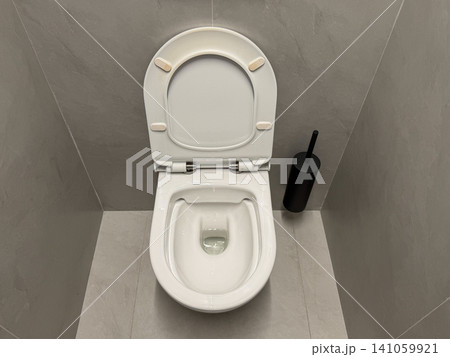 Clean modern toilet inside minimalist restroom with open seat and ceramic sanitary fixture. Hygiene, sanitation, healthcare, facility management, cleanliness, public service, infection prevention 141059921