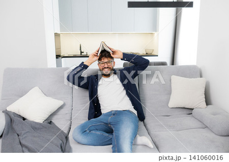 Man reading book and deeply thinking on sofa Man reading book and deeply thinking on sofa 141060016