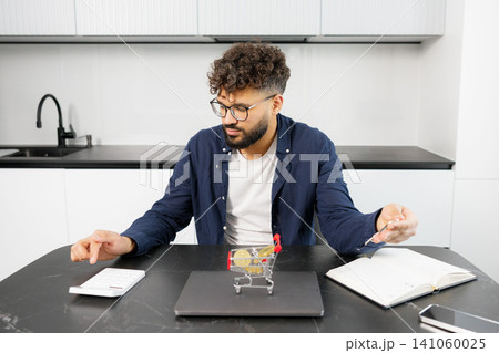 Man analyzing cryptocurrency investment planning on kitchen table Man analyzing cryptocurrency investment planning on kitchen table 141060025