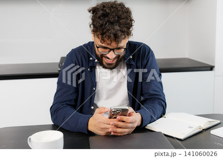 Young man smiling using smartphone at home 141060026